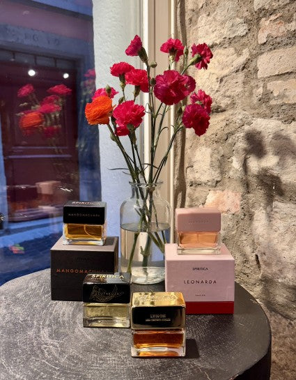 Perfume bottles and flowers on a table with a stone wall background